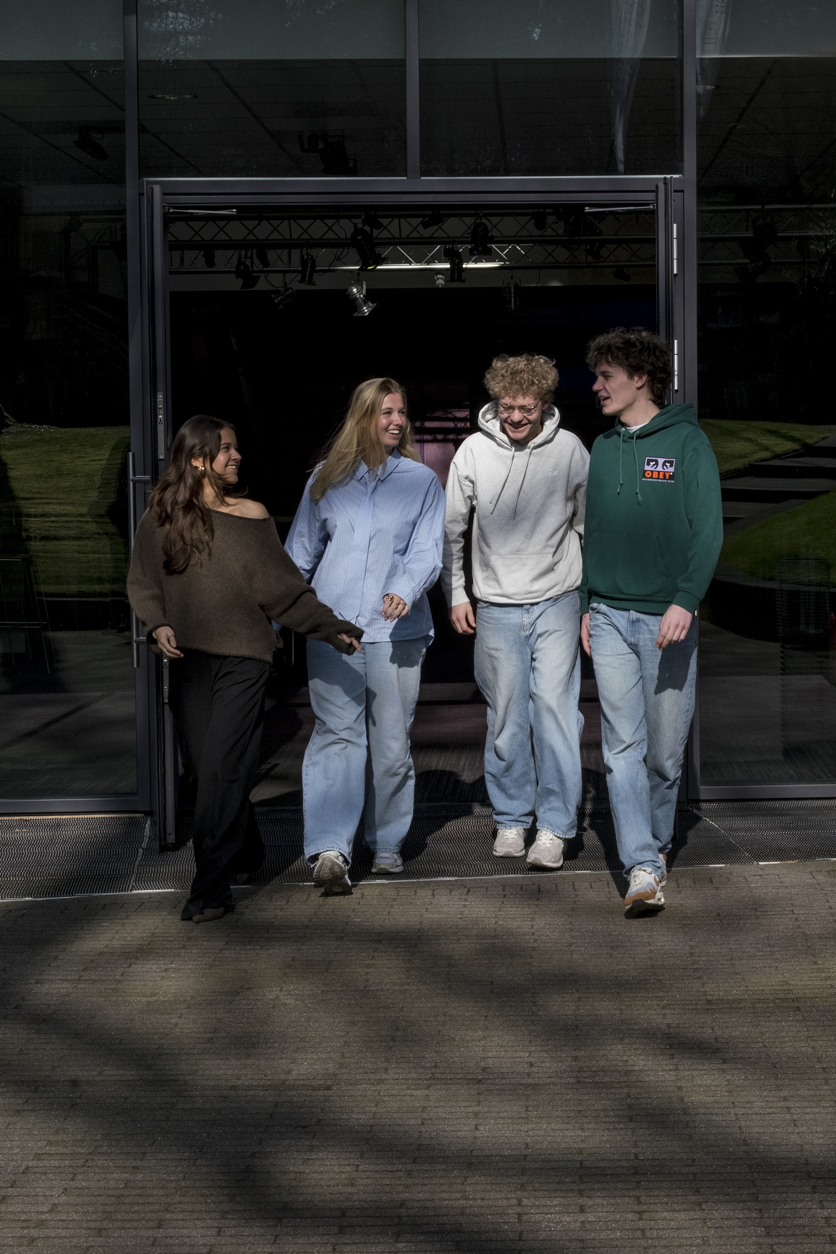 Groep studenten loopt samen naar buiten op een campus