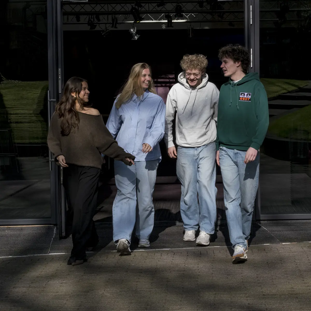 Groep studenten loopt samen naar buiten op een campus