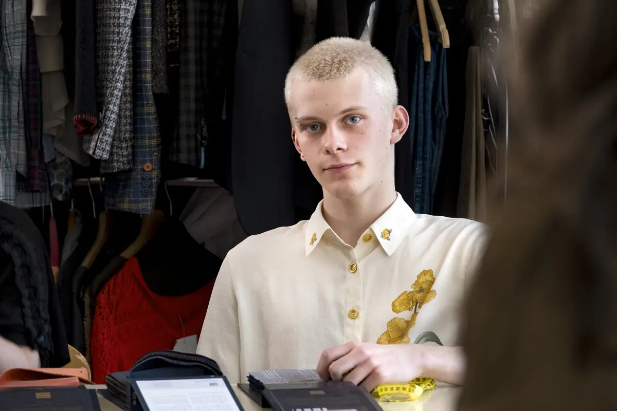 Student bekijkt stoffen tijdens een les in een modeopleiding