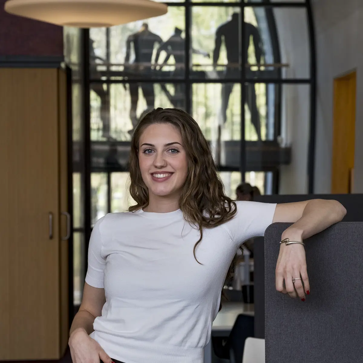 Student staat in een ruimte van een modeopleiding en kijkt in de camera