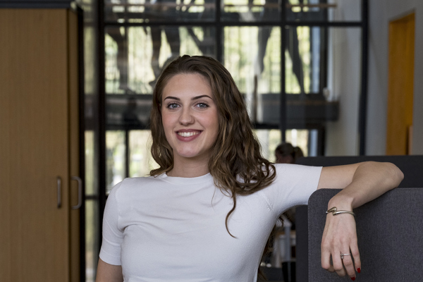 Student staat in een ruimte van een modeopleiding en kijkt in de camera